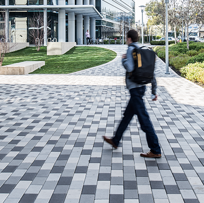 man in backpack walking on pavers by european paving designs